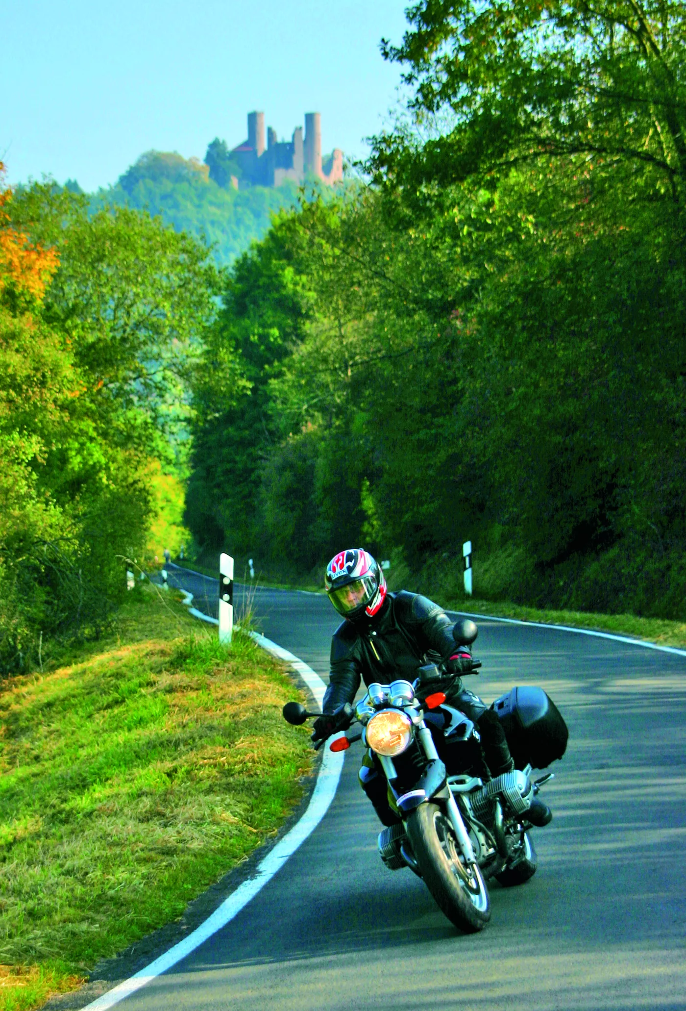 Motorrad auf der Landstraße, oben auf dem Berg die Burgruine Hanstein